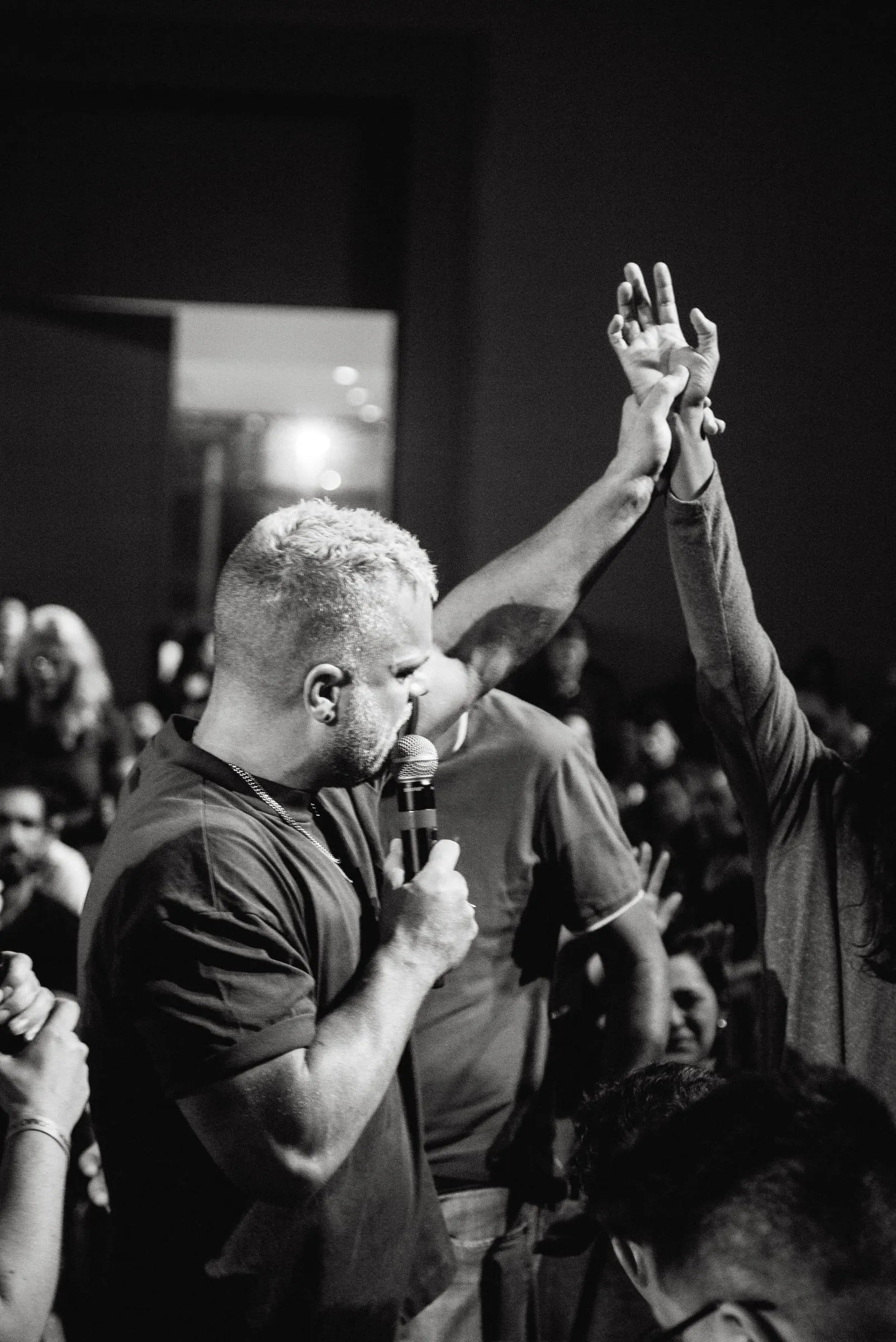 Black-and-white photograph of Shawn Gabie ministering, hands raised in the crowd behind him